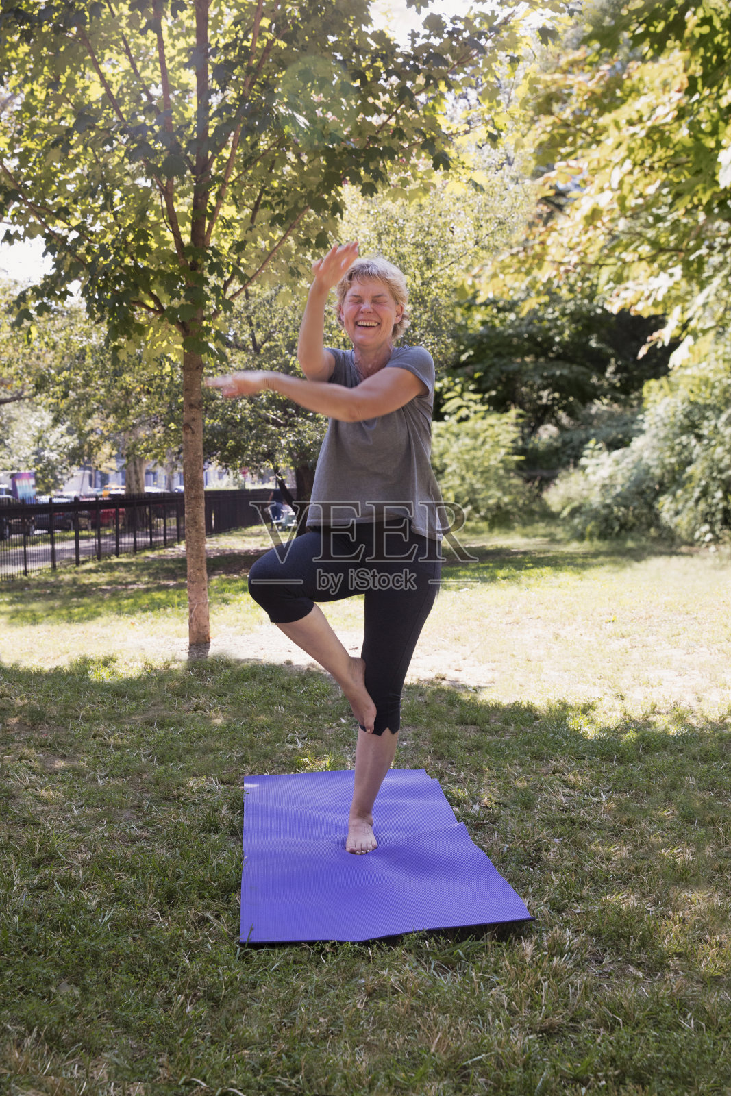 成熟的女人在公园外面用垫子锻炼照片摄影图片