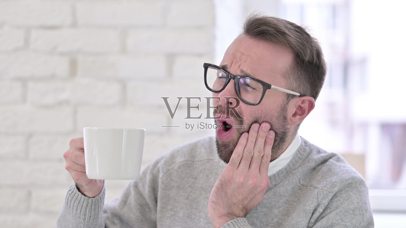 年轻设计师喝咖啡时牙痛照片摄影图片