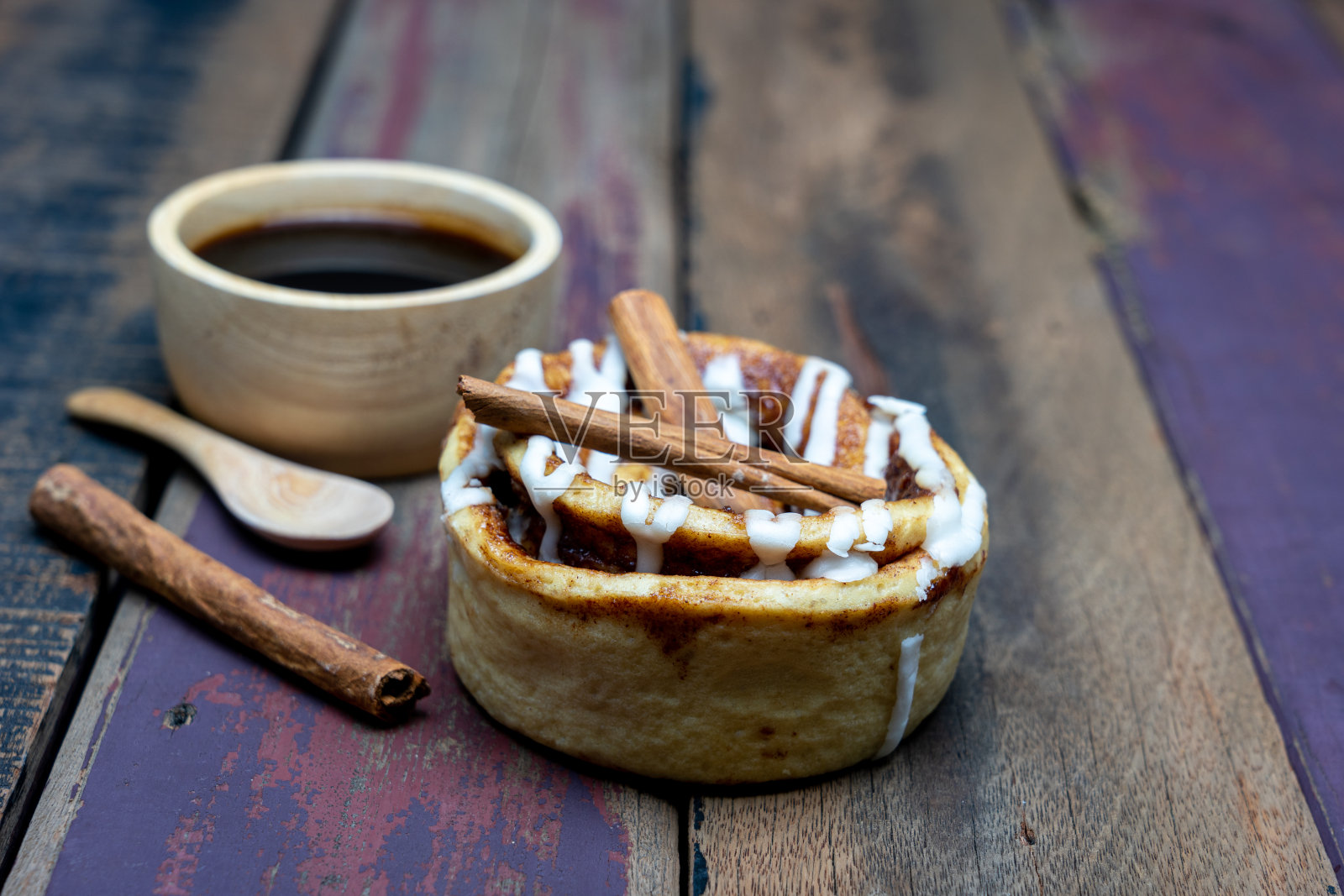 肉桂卷和黑咖啡在木杯与肉桂棒在深色木制背景。照片摄影图片