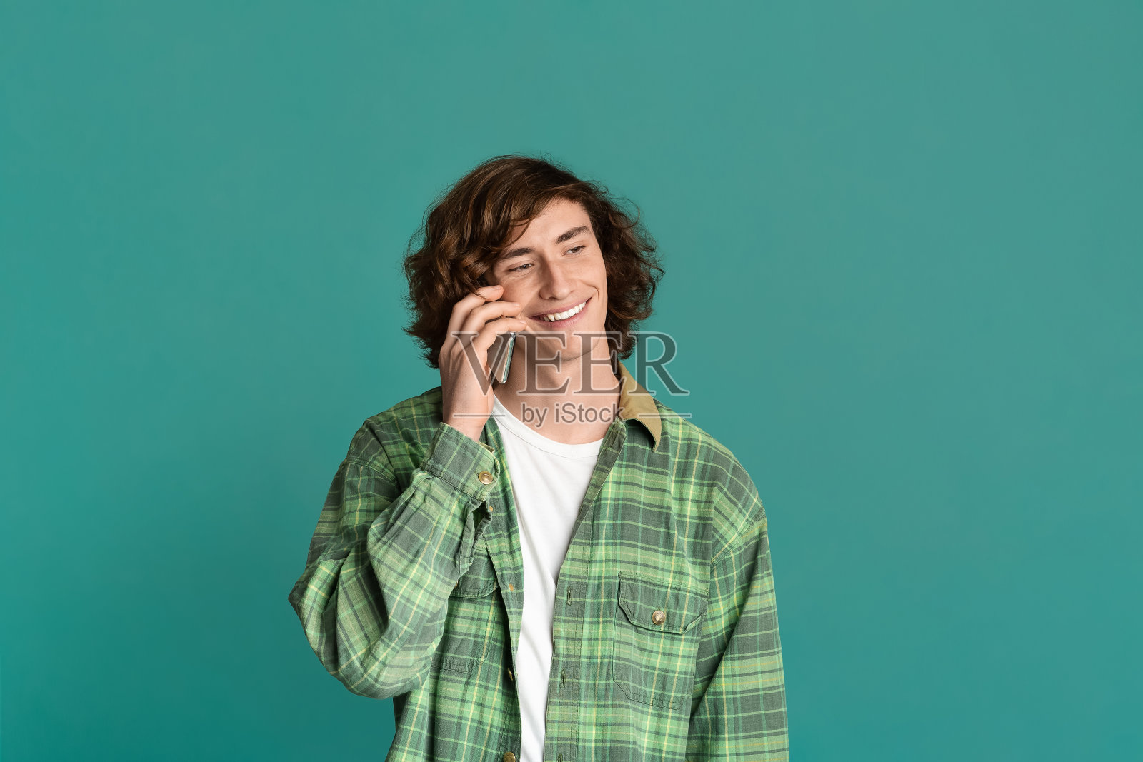 现代通信。一个年轻人在用手机说话,背景是彩色的照片摄影图片