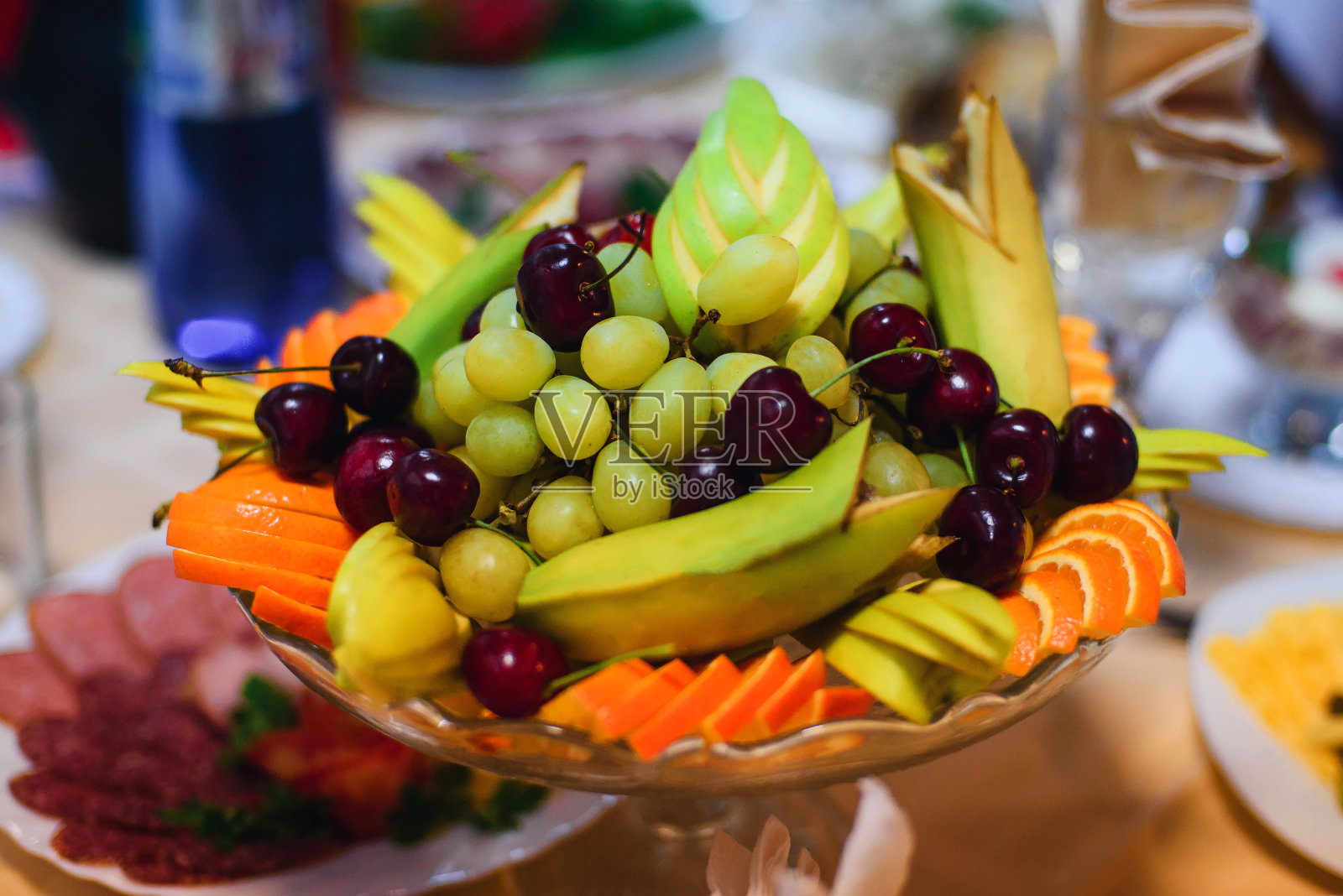 水果盘里有新鲜的葡萄、樱桃、橙子、香蕉和苹果照片摄影图片