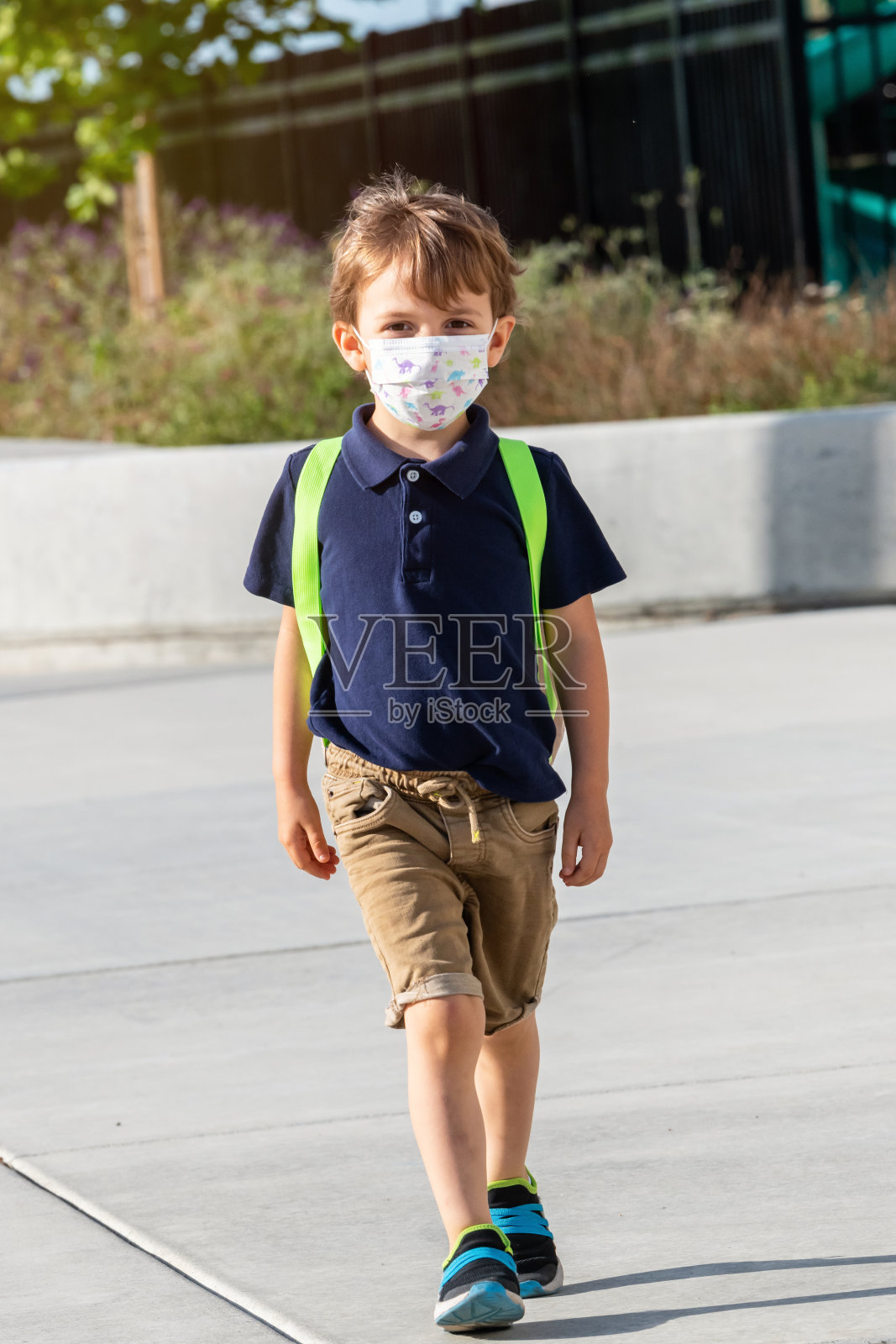 一个戴着防护面具背着背包的小男生照片摄影图片