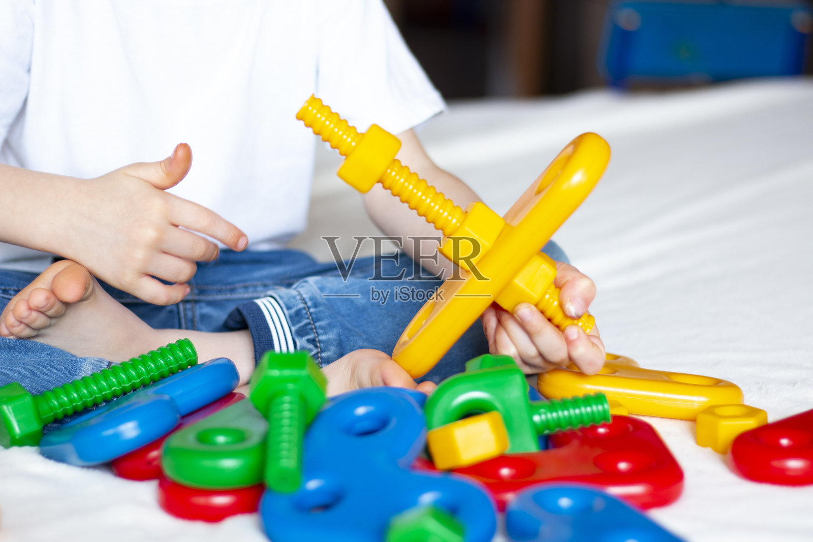孩子坐在床上,用构造器做了一个黄色的飞机。儿童的创造力和学习能力。家庭休闲。照片摄影图片