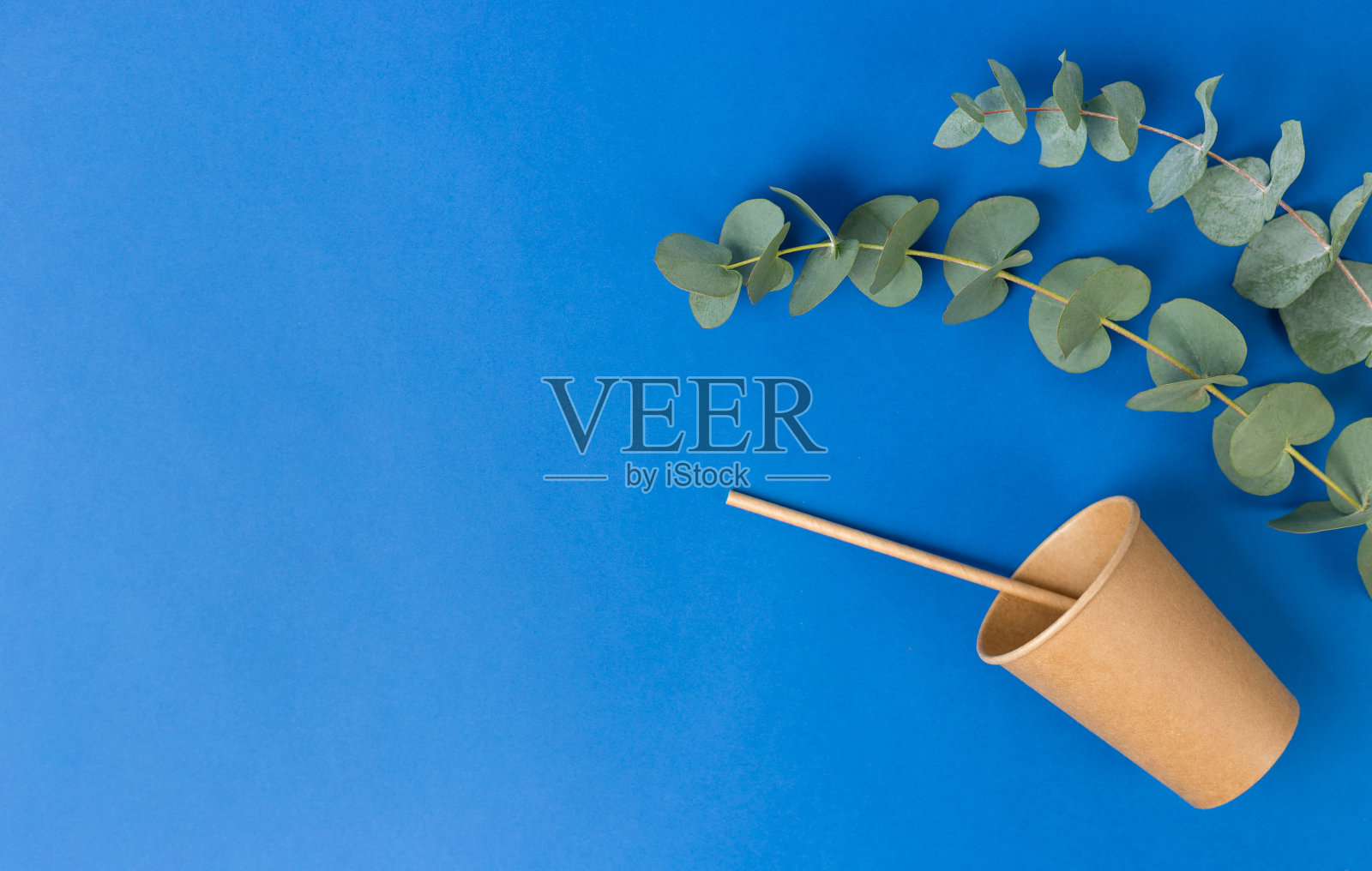 工艺生态杯与纸管美味的饮料和桉树叶在蓝色的背景。零浪费,环保理念。平的。可持续的生活照片摄影图片