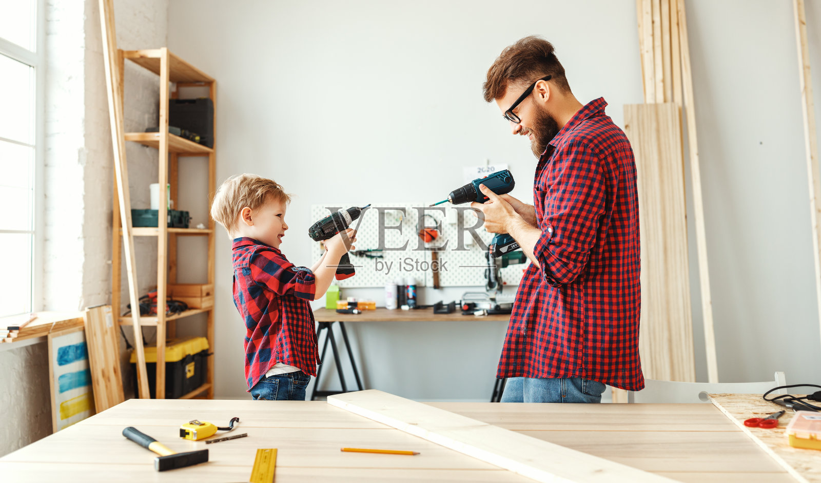 父亲和儿子在车间玩钻机照片摄影图片