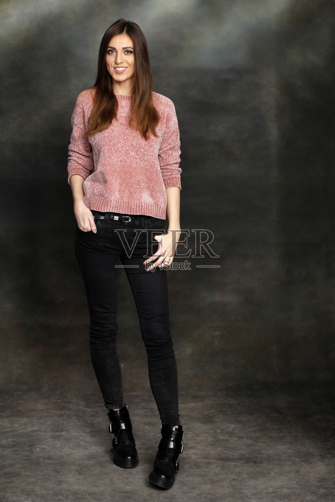 美丽,积极的黑发女孩摆姿势在工作室的画布背景。照片摄影图片