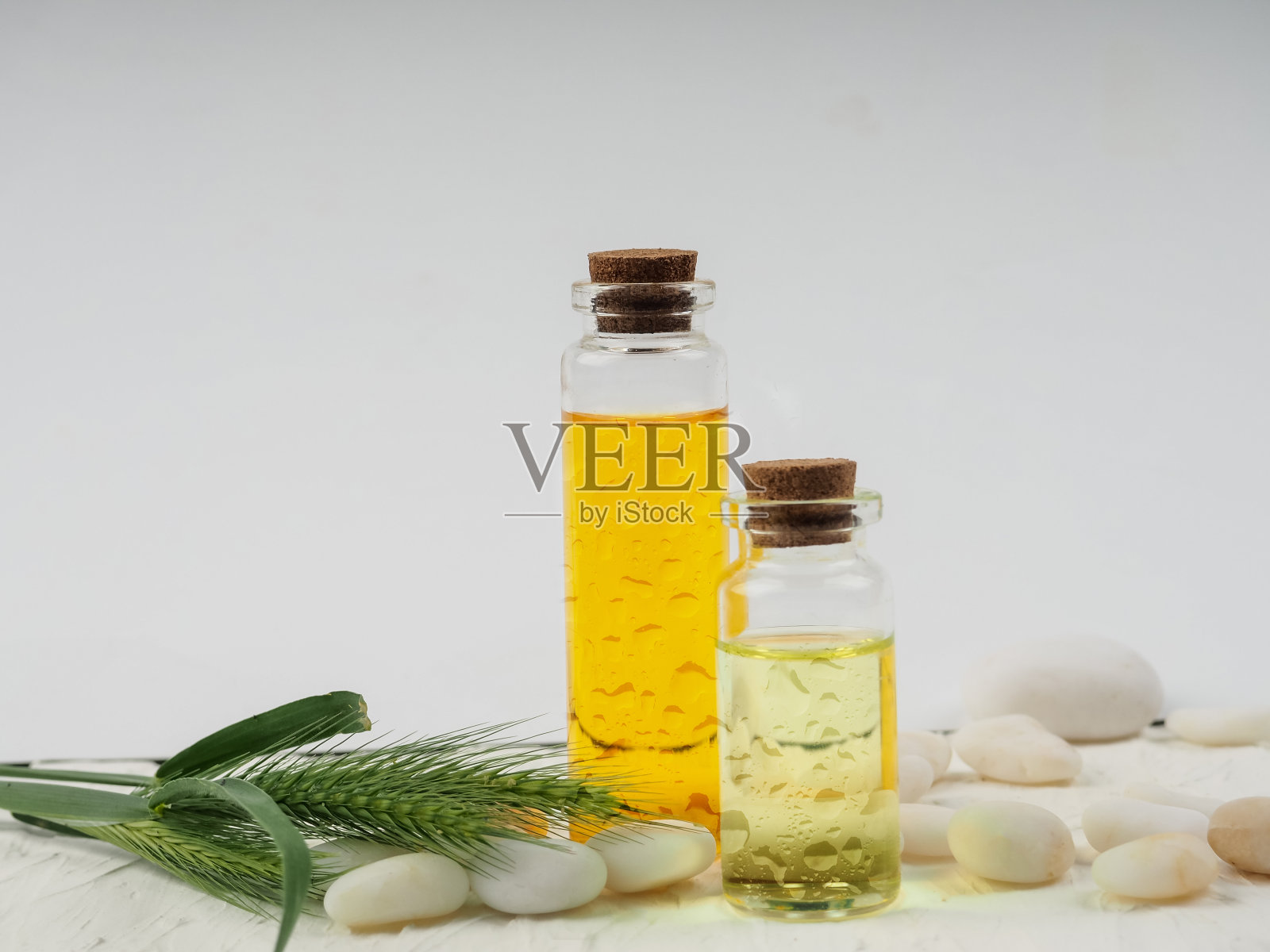 白色背景上的两瓶化妆油,旁边是鹅卵石。健康理念,Spa。白底香精油,照片摄影图片