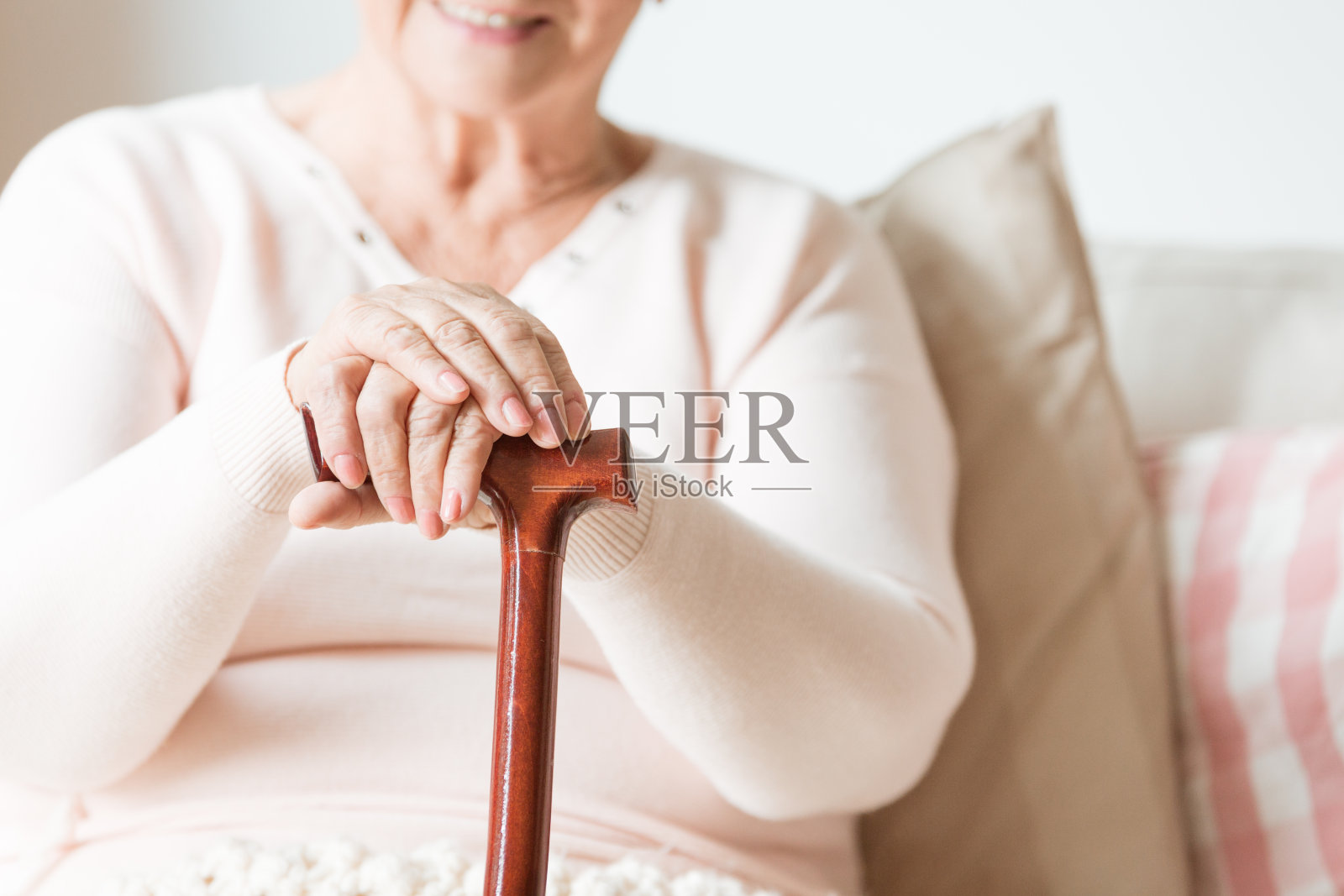 一个快乐的老妇人的手的特写,在一个木制的手杖上休息照片摄影图片