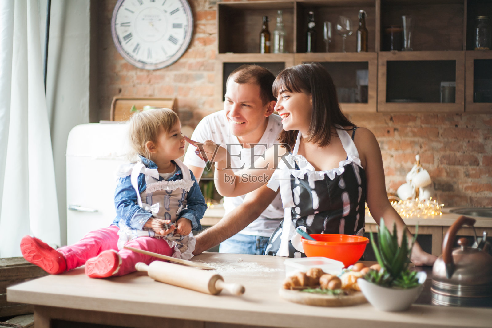 可爱的小女孩和她美丽的父母在厨房做饭的时候微笑着照片摄影图片