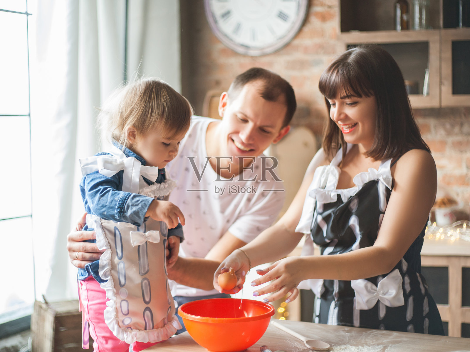 可爱的小女孩和她美丽的父母在厨房做饭的时候微笑着照片摄影图片