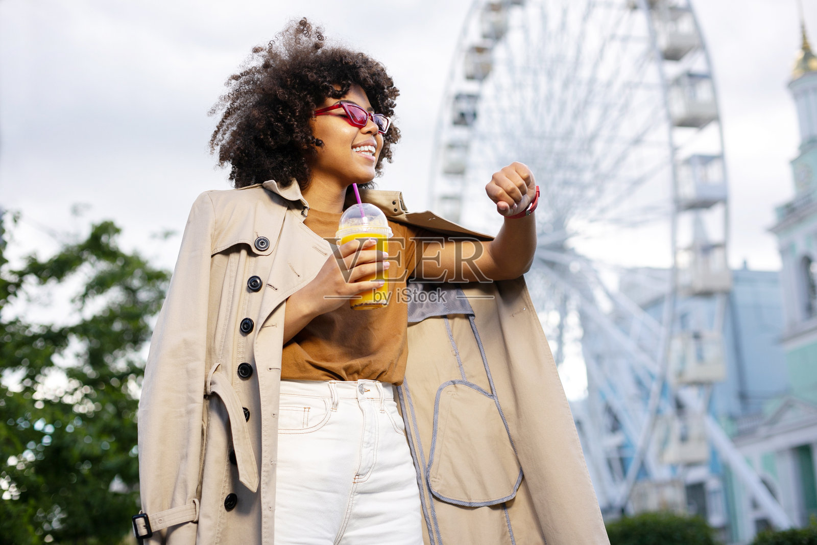 乐观的女人看着手表,拿着一杯果汁照片摄影图片