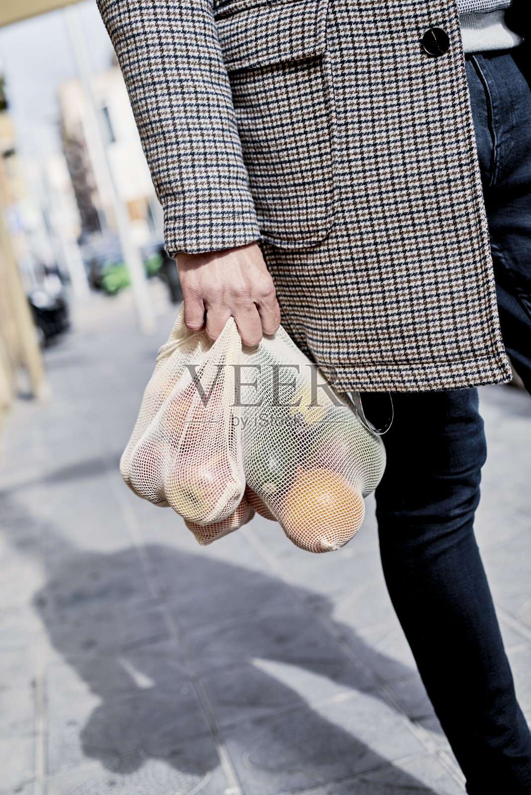 男人背着一个装满水果和蔬菜的网袋照片摄影图片