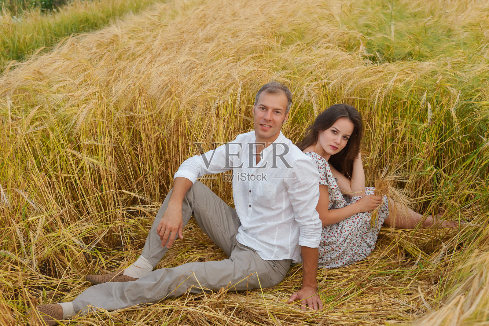 一对幸福的夫妇坐在麦田里的草地上照片摄影图片