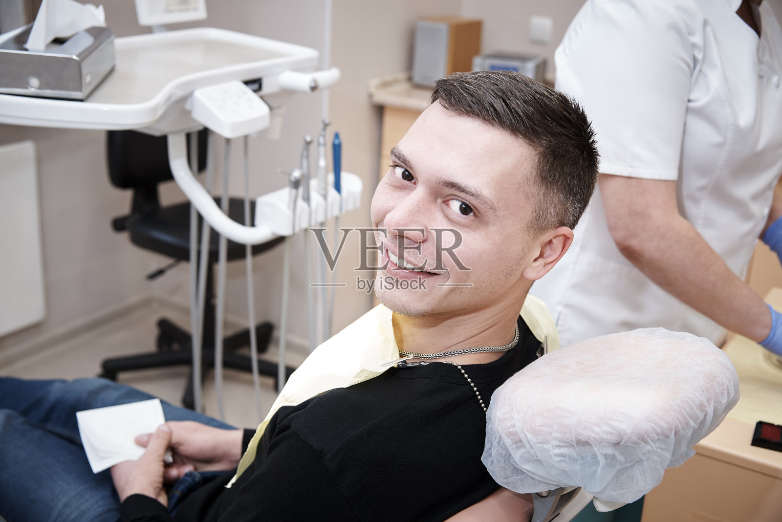 快乐的年轻人坐在牙科椅上。照片摄影图片