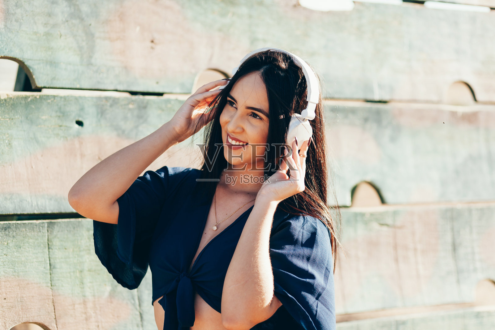 一位年轻女子在一个阳光明媚的日子里戴着耳机在公园里听音乐照片摄影图片