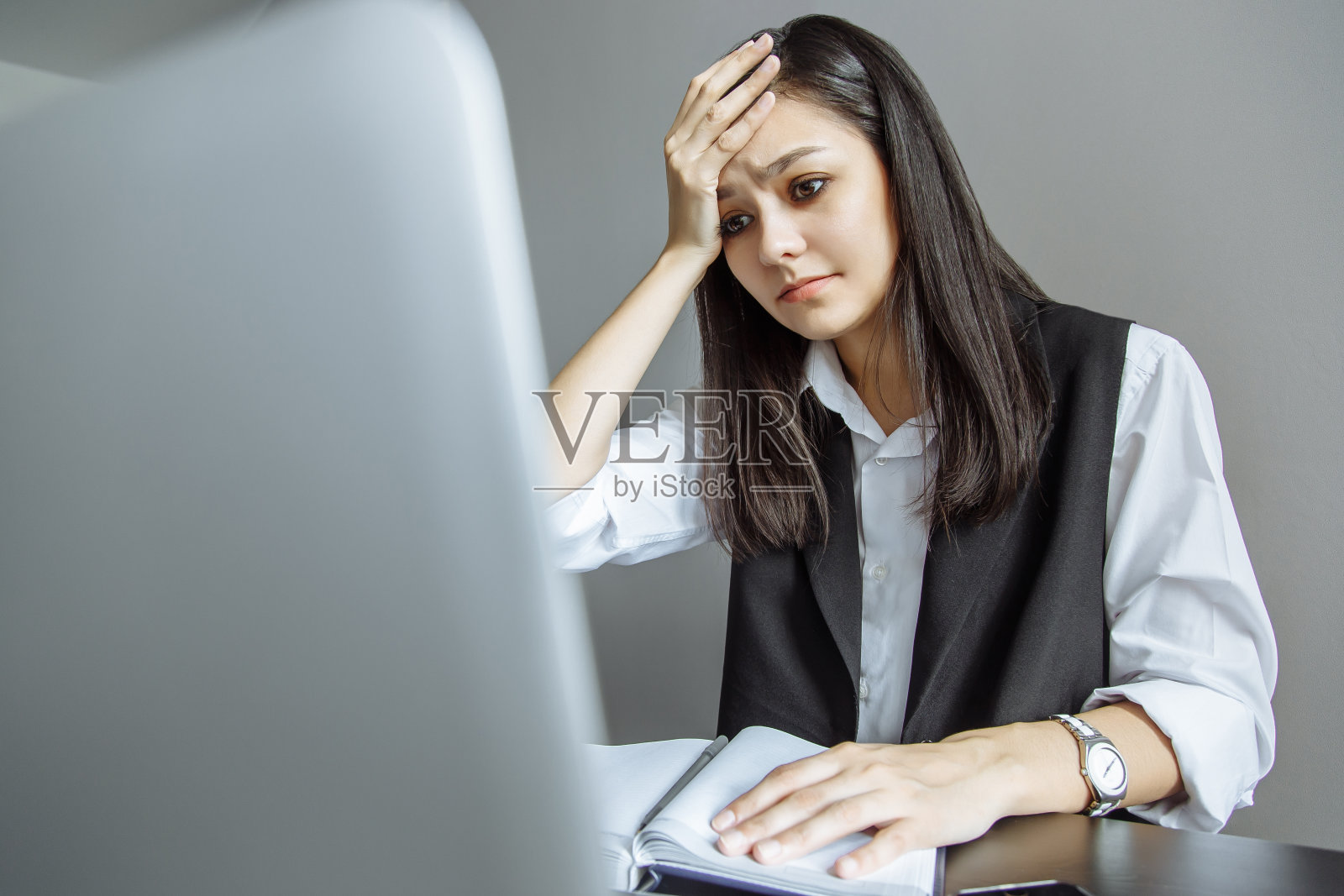 沮丧的年轻女子抱着她的头坐在工作场所照片摄影图片