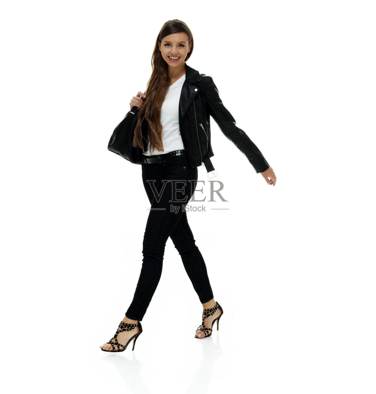 白人女性穿着皮夹克,拿着钱包走在白色背景前照片摄影图片