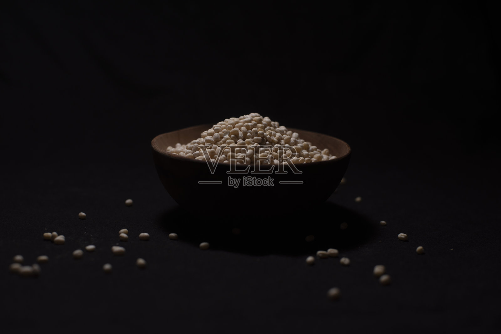 一碗印度豆类,点缀着散落的谷物在黑暗的复制空间背景。照片摄影图片