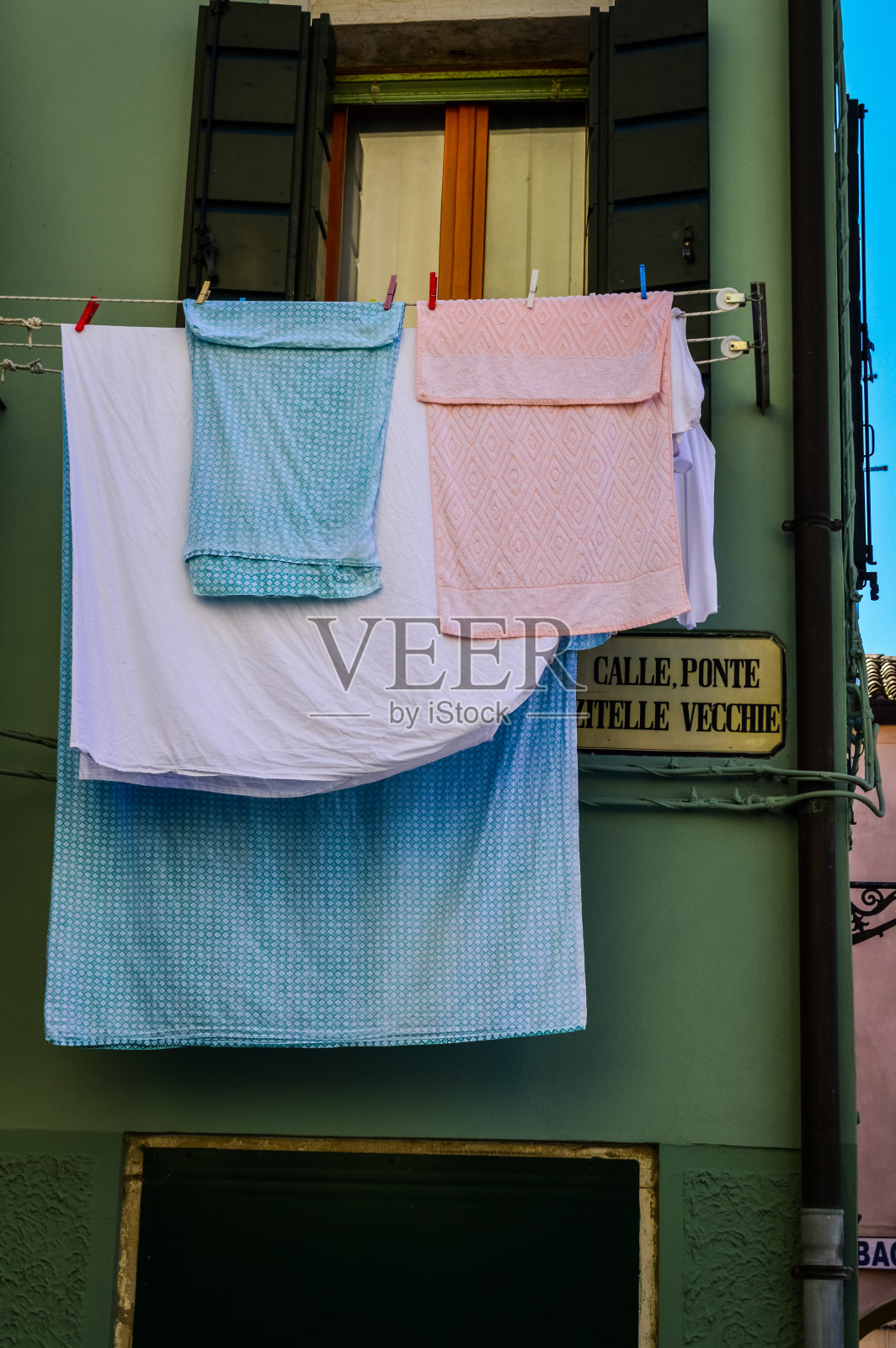在意大利威尼斯附近的Chioggia大街上,洗好的衣服挂在窗户外面。照片摄影图片