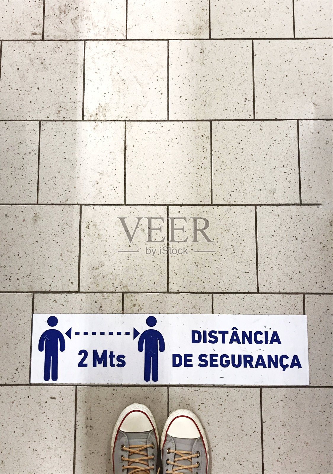 站在贴着红线的瓷砖地板上,红线上写着“保持距离”。保持距离的概念,社交距离。胶片颗粒。照片摄影图片