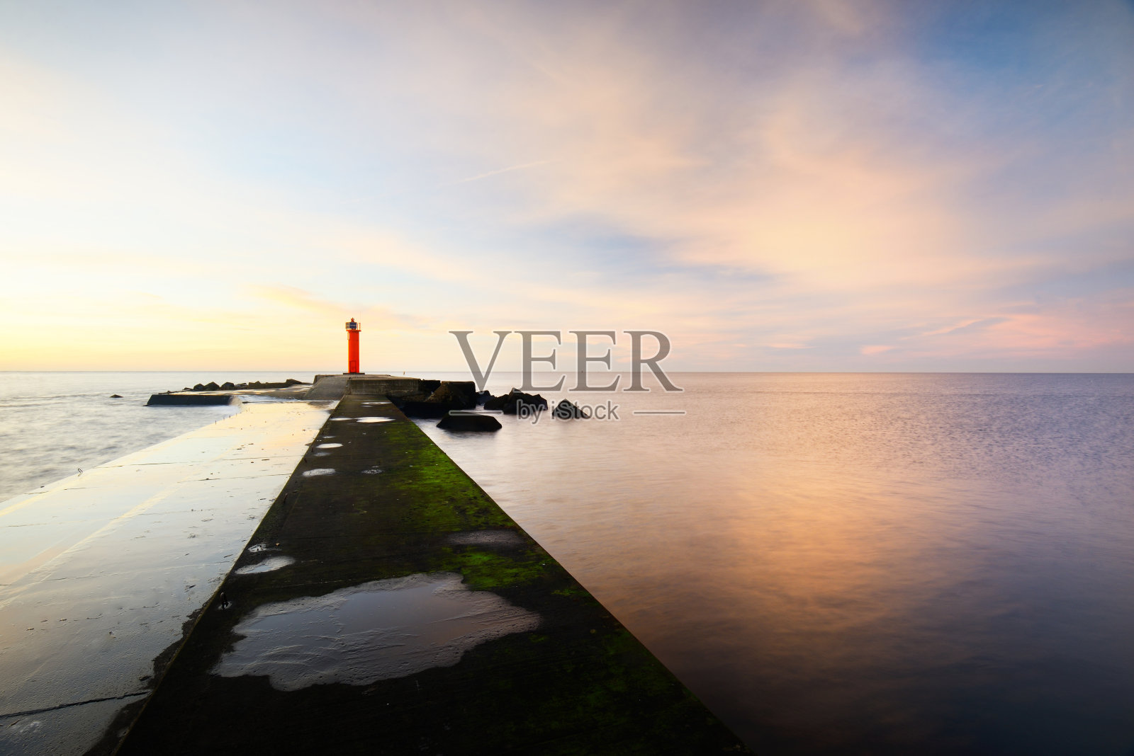 一个空的散步到橙色的灯塔与太阳能电池对彩色日落天空。惊人的cloudscape。长时间的曝光。环境保护主题。波罗的海,拉脱维亚里加湾照片摄影图片
