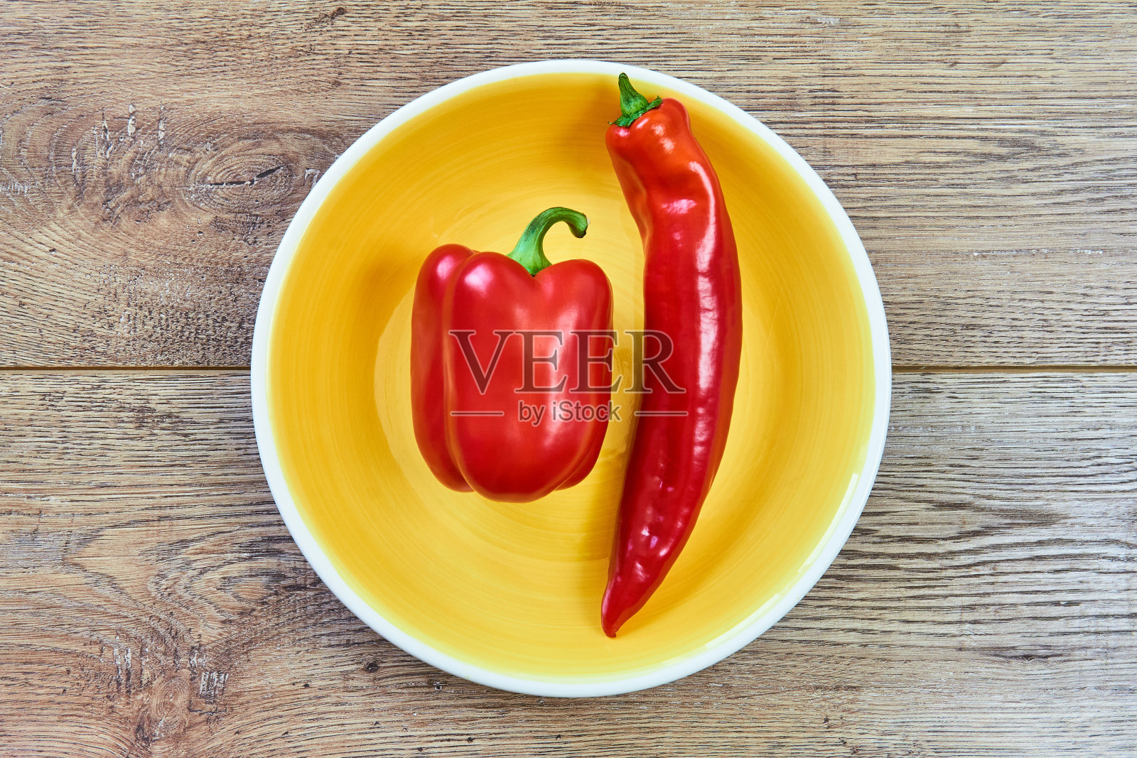 木桌上的黄色盘子里放着各种甜椒的豆荚,有薄有厚照片摄影图片