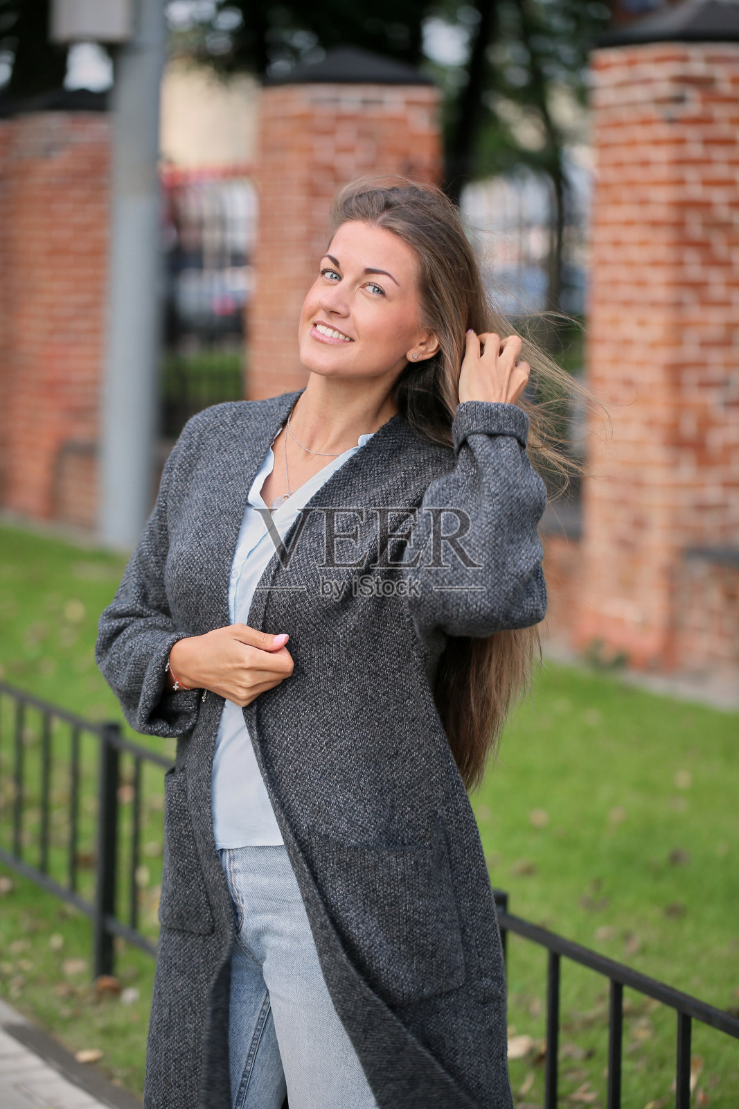 浪漫开朗的年轻女子。一个漂亮的女孩的肖像,穿着牛仔裤,蓝色衬衫,和一件浅外套。走在城市的街道上。照片摄影图片