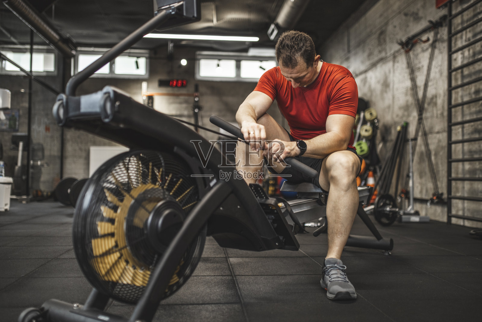 男子在健身房里使用划船机照片摄影图片