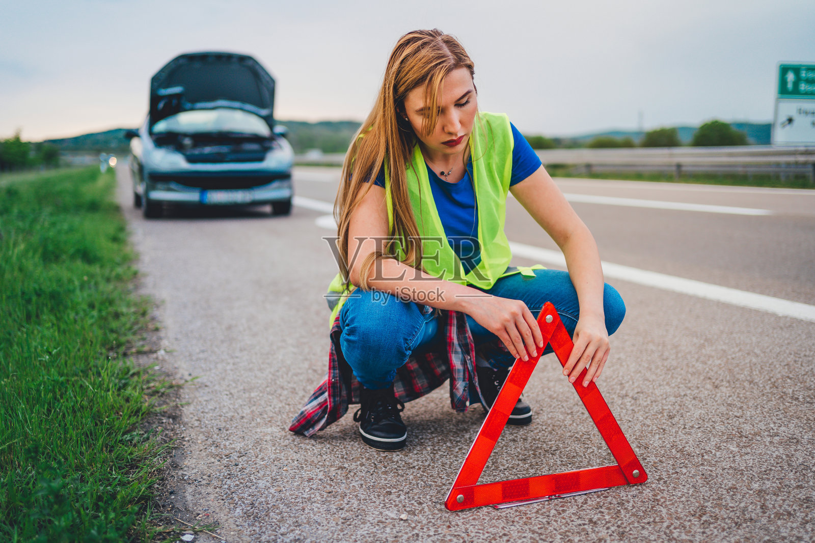 女人把三角形警告标志放在路上照片摄影图片