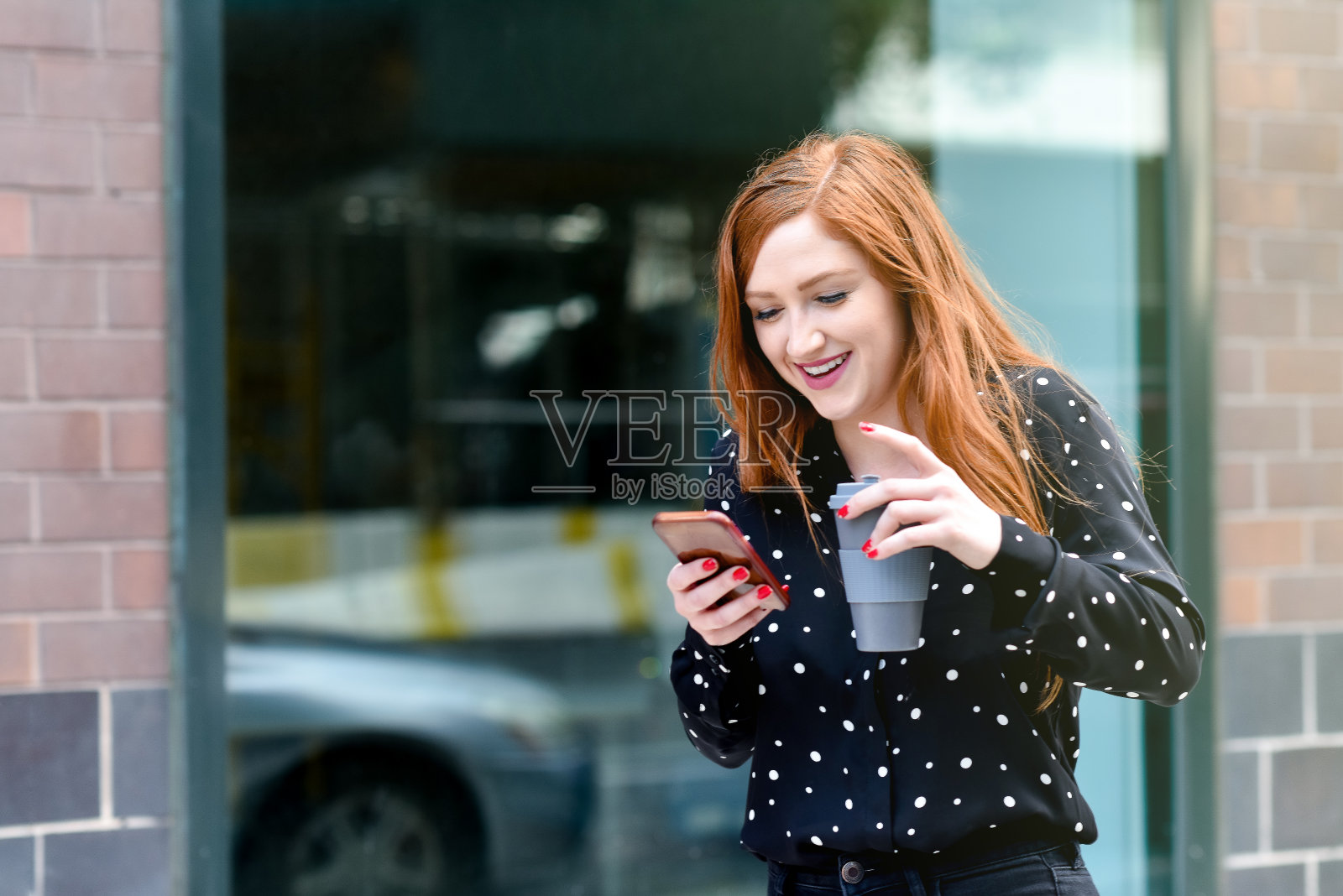 年轻的红头发女人拿着咖啡和电话笑照片摄影图片