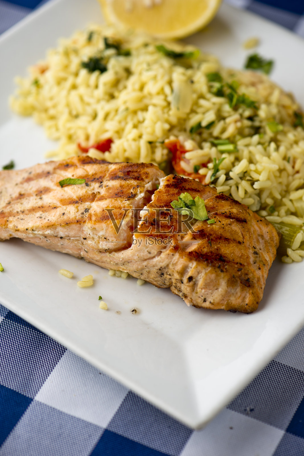 鲑鱼排,烤鱼和大蒜sautéed蔬菜。经典餐厅海鲜最爱。整条鱼,烤皮,搭配柠檬蔬菜,土豆,意大利欧芹和酸豆。照片摄影图片