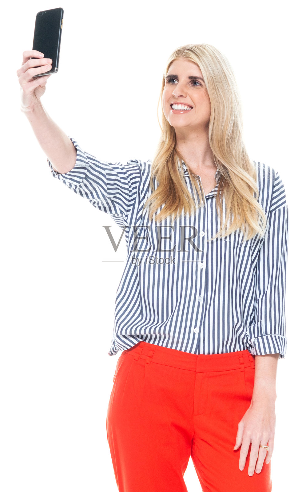 白种人年轻女性站在白色背景前,穿着智能便服,使用手机拍照照片摄影图片