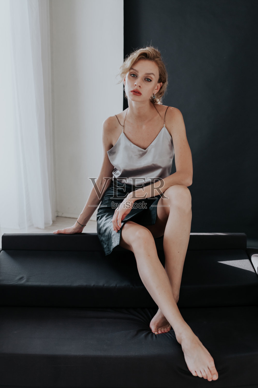 一个漂亮时尚的金发女人坐在黑色办公室沙发上的肖像照片摄影图片