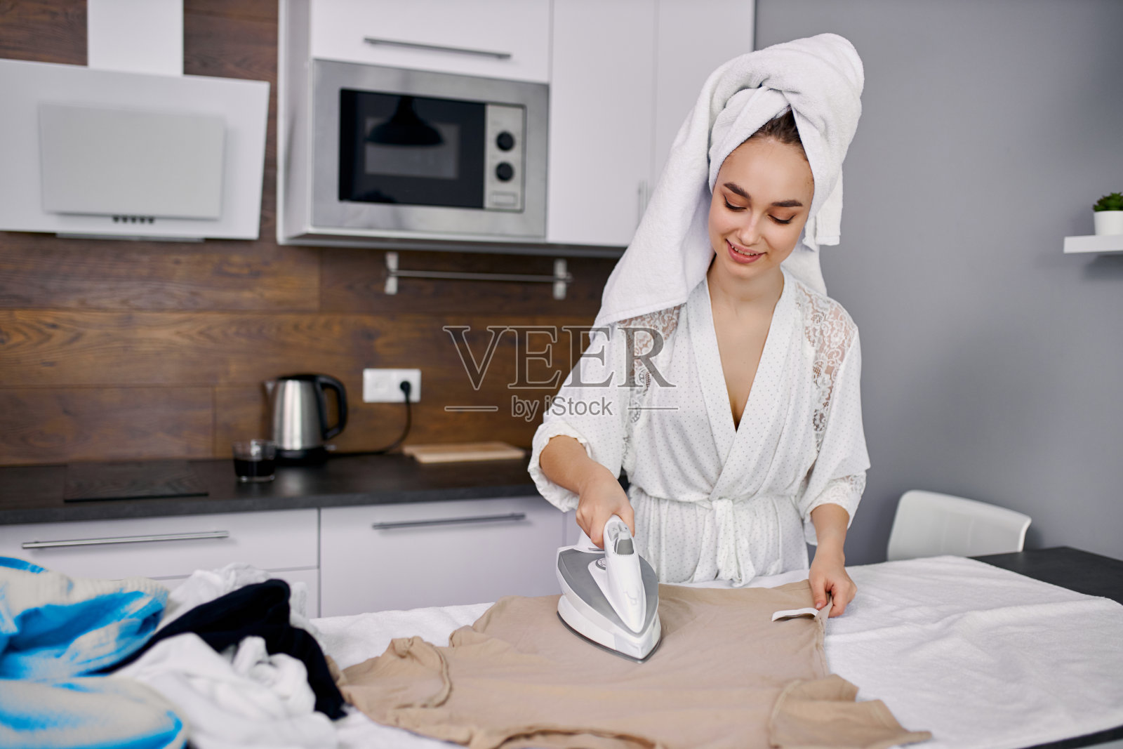 可爱的年轻主妇正在细心地熨衣服照片摄影图片