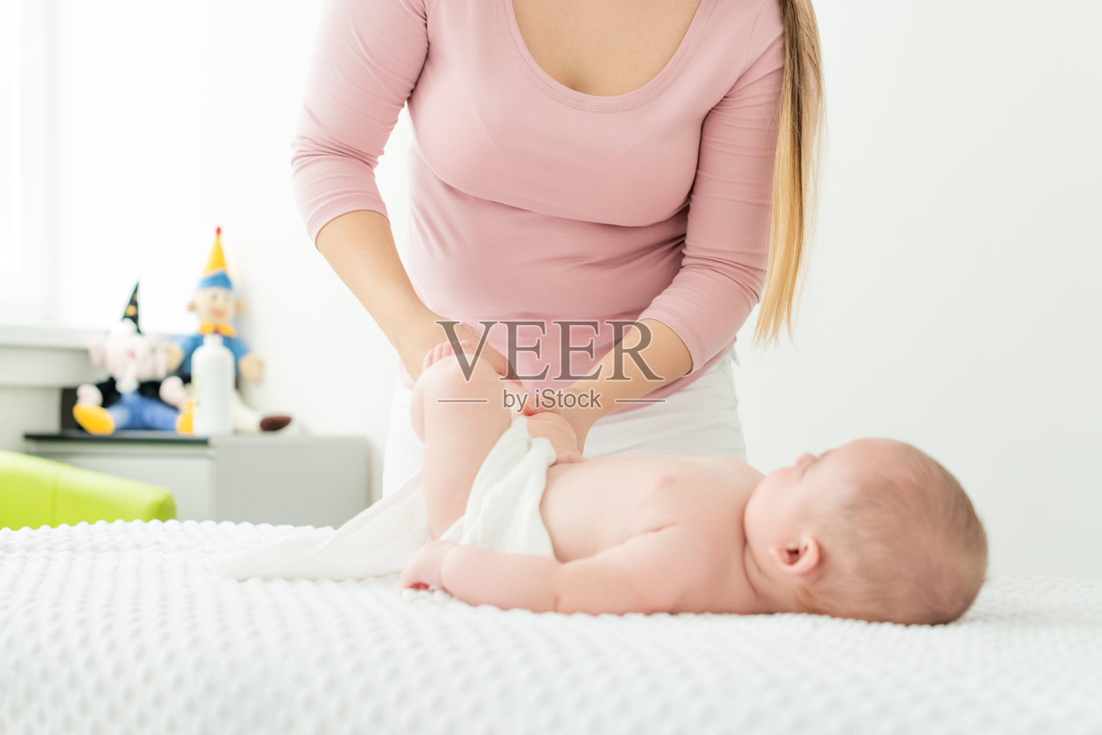 宝宝按摩:儿童理疗师为男婴涂抹按摩油,母亲为新生儿按摩照片摄影图片