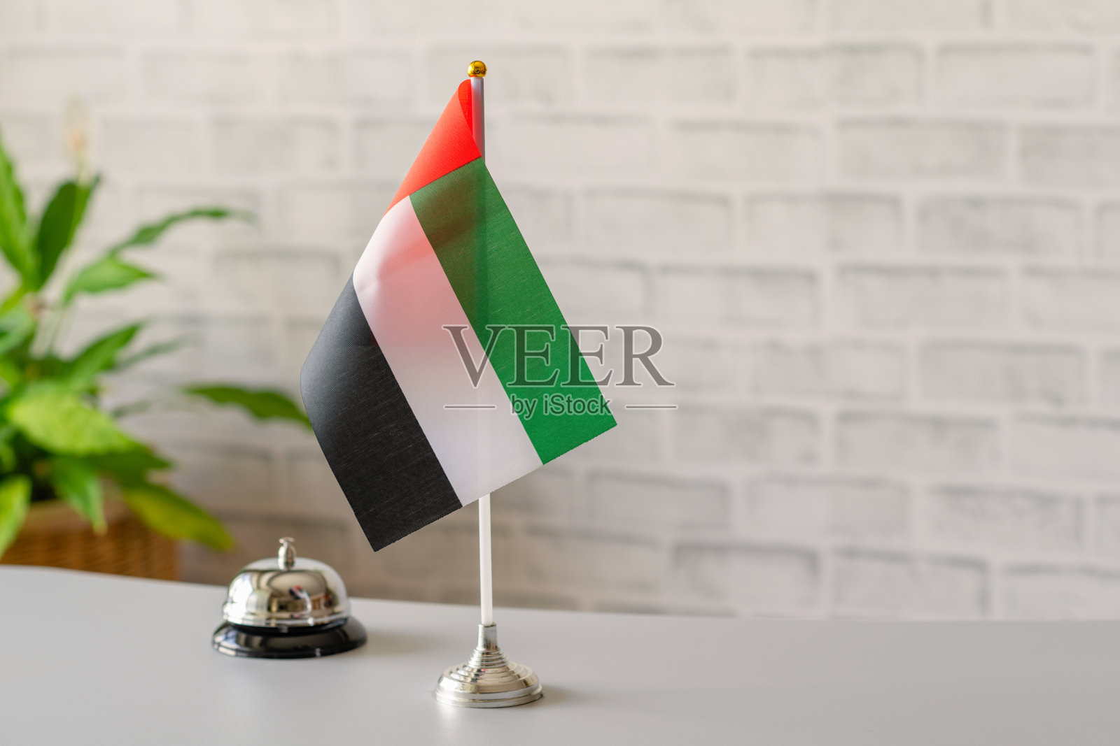 前台的银色复古铃铛,带有阿拉伯联合酋长国国旗,有复制空间。酒店服务。旅行,旅游。选择性聚焦。概念。照片摄影图片