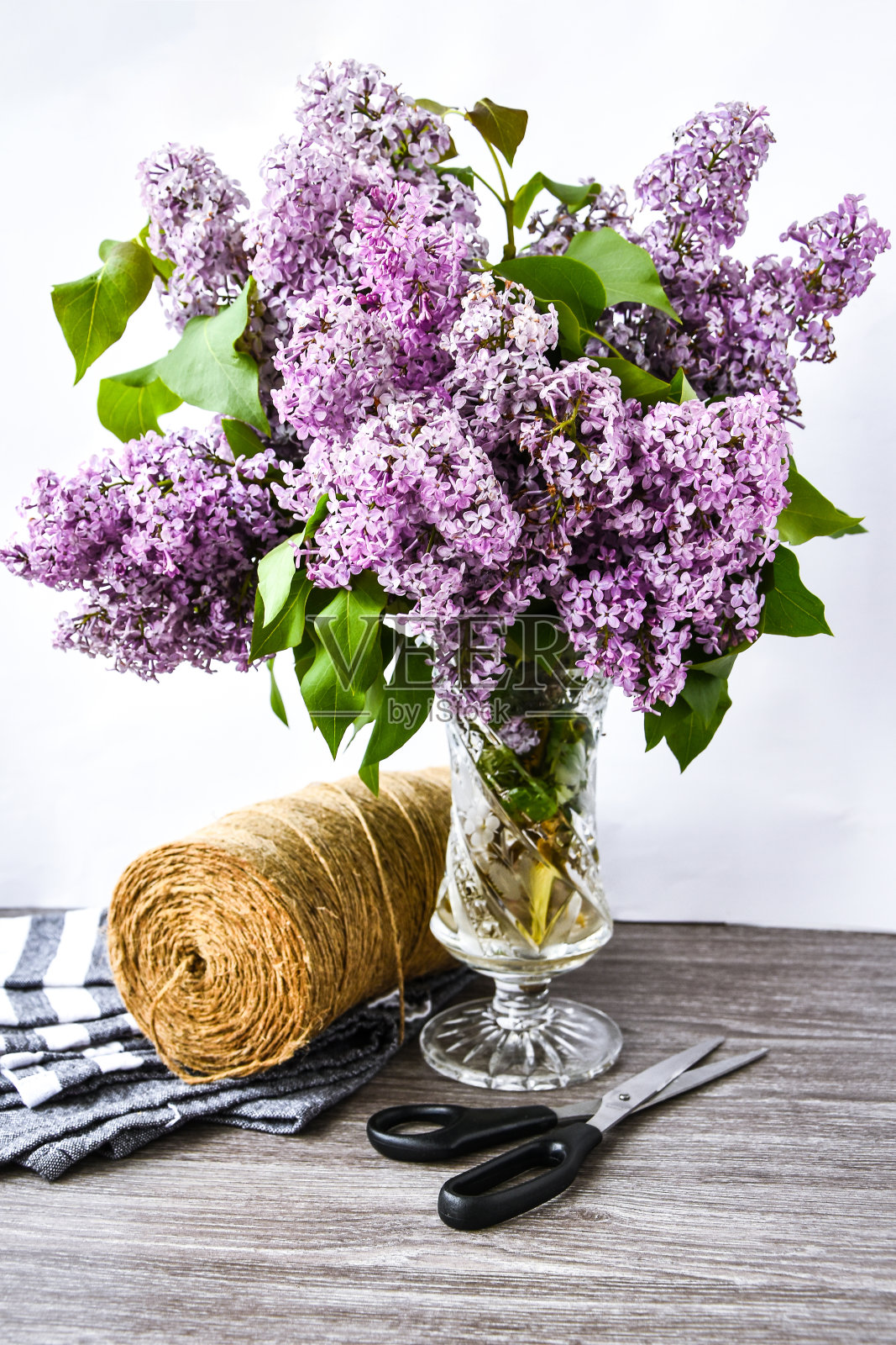 桌上的玻璃花瓶里装着丁香花束,还有剪刀和绳子照片摄影图片