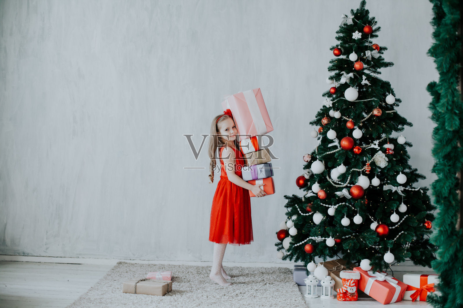 小女孩打开圣诞礼物,装饰新年树照片摄影图片