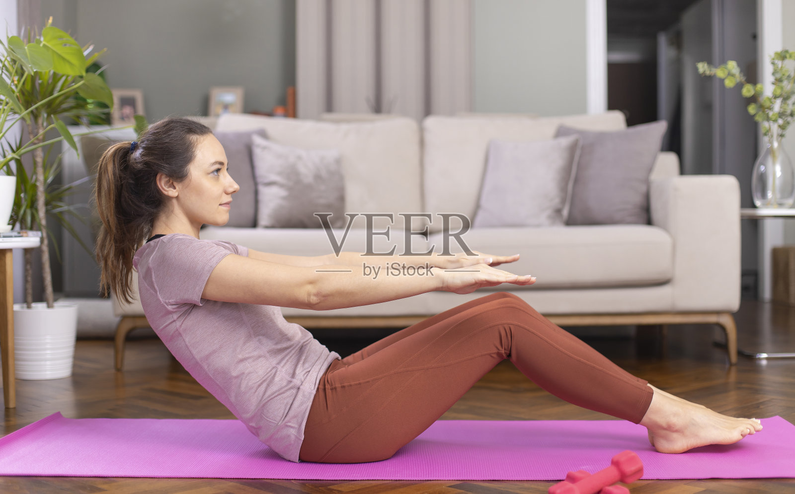 运动的年轻女子在运动垫上做仰卧起坐照片摄影图片