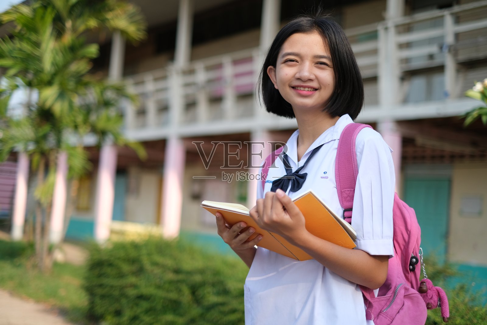 快乐的学生穿着书本校服在学校。照片摄影图片