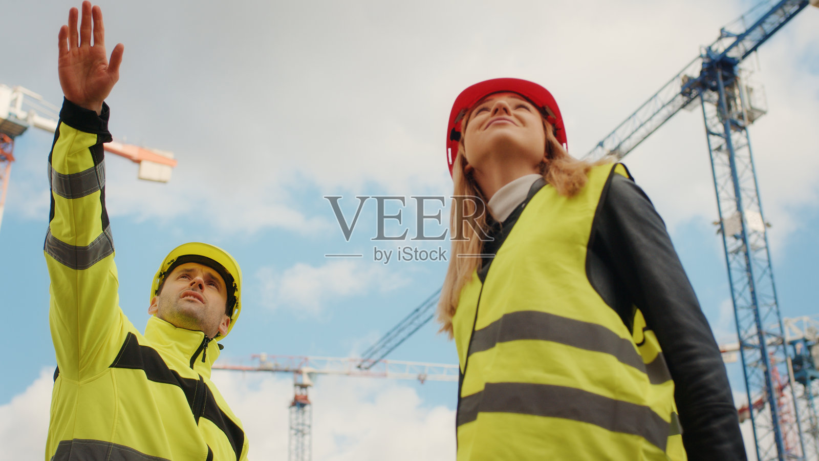 建筑工程师监督建筑工地。指向起重机照片摄影图片