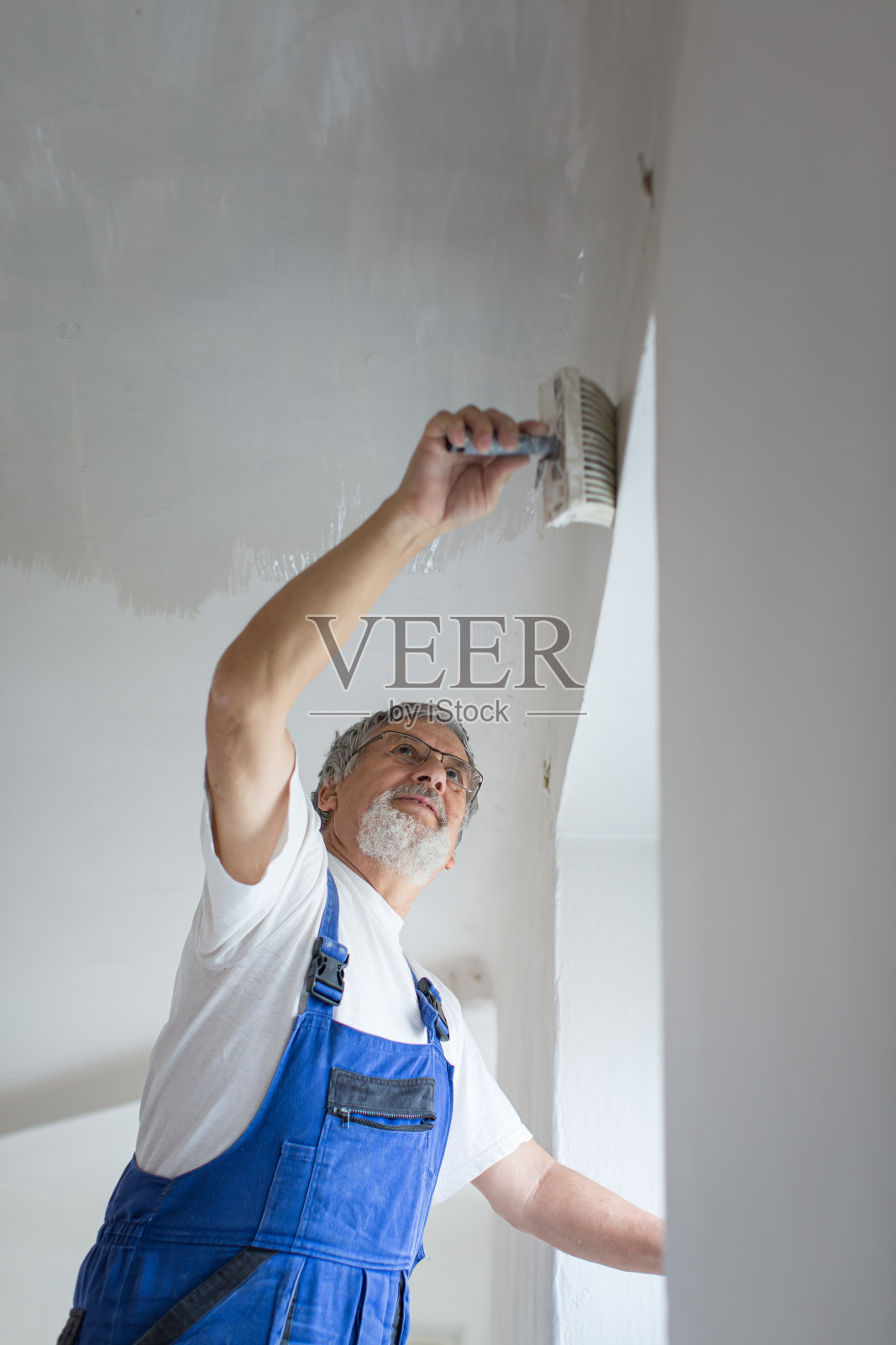 一位老人正在粉刷出租公寓的房间照片摄影图片