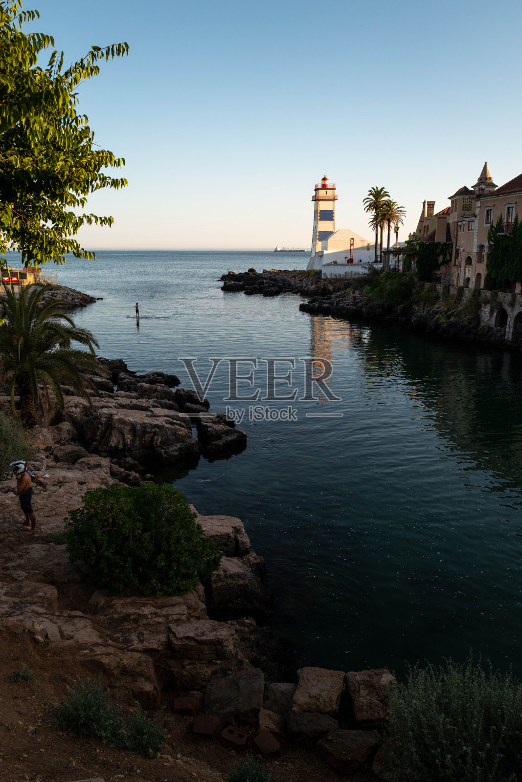 一个男人在凯斯卡斯的圣玛利亚灯塔下划水。照片摄影图片