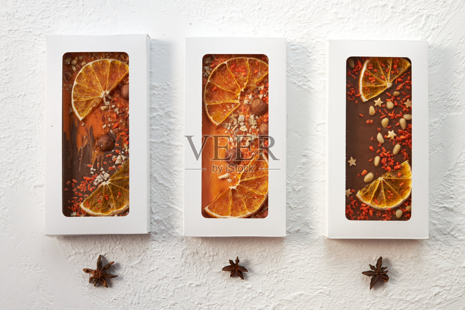 三个手工巧克力棒,坚果和干果在白色的背景上照片摄影图片