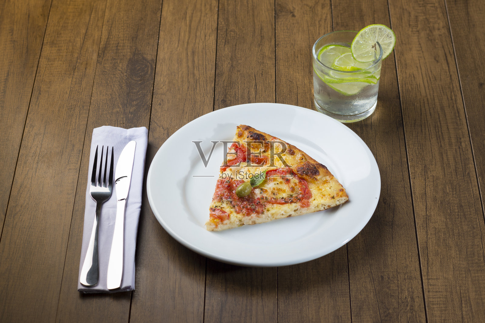 用马苏里拉奶酪、西红柿、罗勒叶和绿橄榄制成的雏菊比萨。苏打水和柠檬。用木头烤炉做的。照片摄影图片