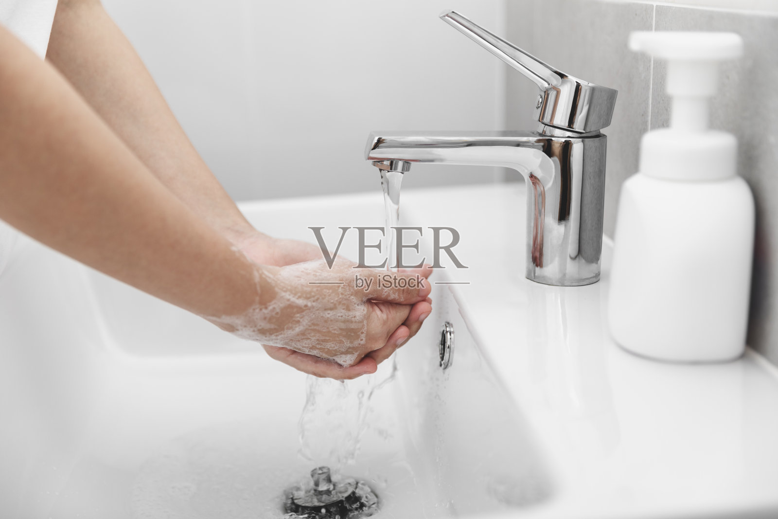 妇女使用肥皂和在水龙头下洗手以预防冠状病毒。照片摄影图片