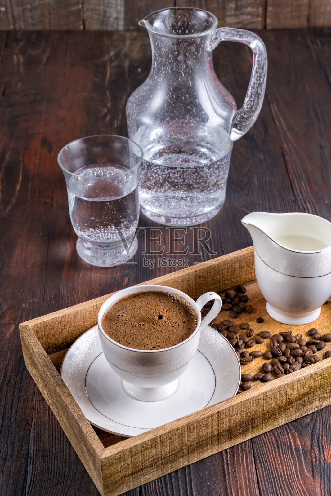 一杯咖啡,咖啡豆和牛奶装在一个木盒里,背景是深色的木头。照片摄影图片