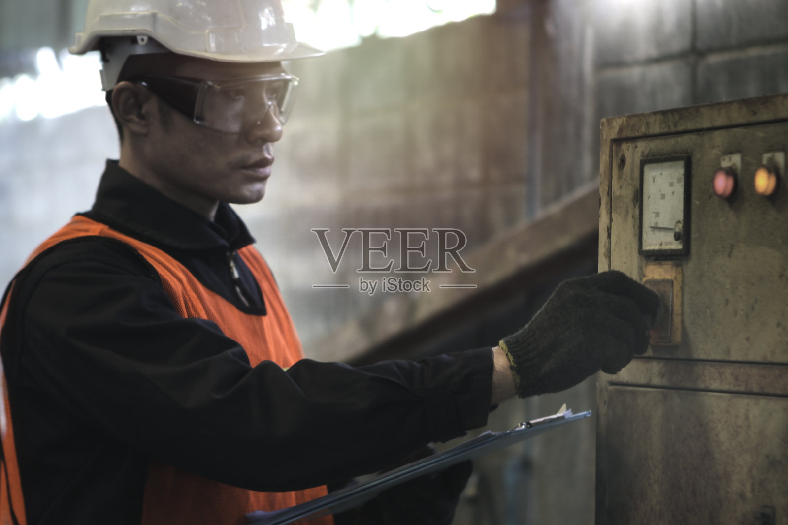 工业工程师工人戴着头盔和安全眼镜,指着和触摸仪表板按钮的制造厂工厂,年轻的男子在工业工作照片摄影图片