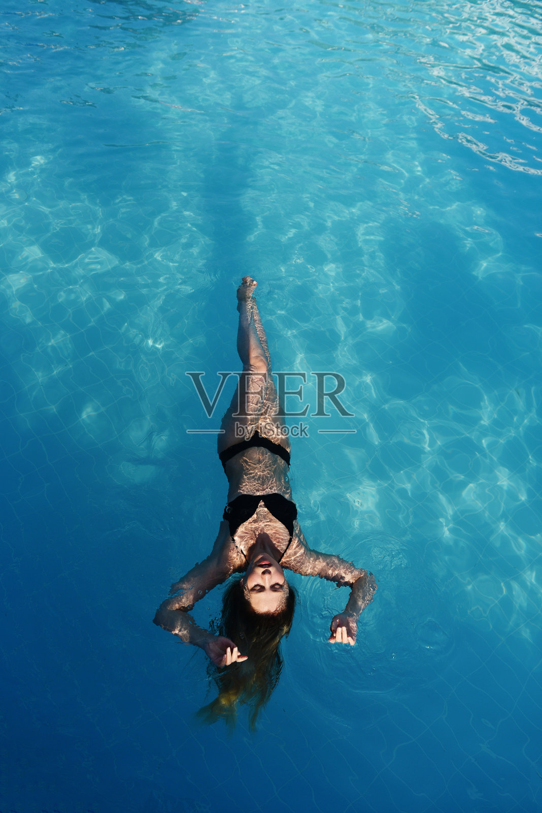 俯视图美丽的女性在游泳池的背景。照片摄影图片