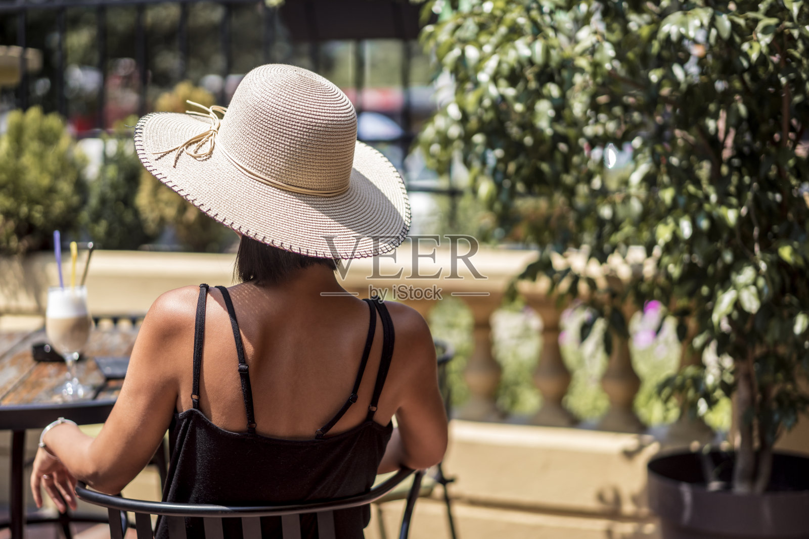 美丽的年轻女子与帽子在咖啡馆喝咖啡在晴天照片摄影图片